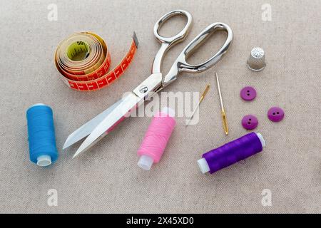 Utensili e accessori per cucire. Forniture per cucire, fili, aghi, forbici, perni, bottoni e un metro a nastro per cucire. vista dall'alto Foto Stock