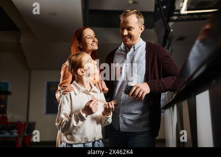 Un uomo e una donna stanno insieme alla figlia, incarnando unità e amore, godendo di un momento speciale al cinema come una famiglia felice. Foto Stock