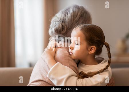 Piccola ragazza che abbraccia una donna più anziana sul divano Foto Stock