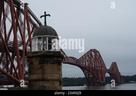 Incredibile struttura del ponte ferroviario Firth of Forth con un pittoresco faro in primo piano. Foto Stock