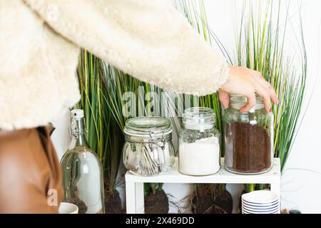 Persona irriconoscibile mano che raccoglie un vaso di vetro pieno di caffè Foto Stock