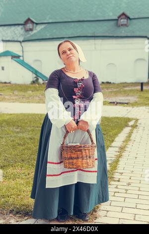 Ritratto di una donna bruna vestita con abiti barocchi storici e acconciature di vecchia moda, all'aperto. Abito medievale della classe operaia Foto Stock