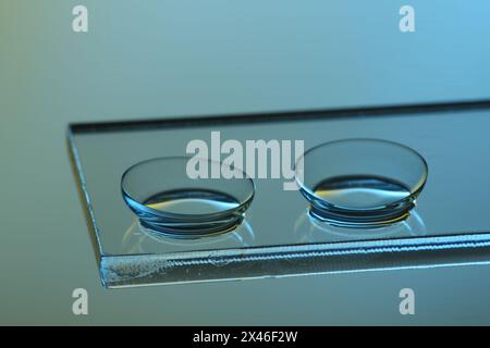 Coppia di lenti a contatto su vetro su sfondo azzurro, primo piano Foto Stock
