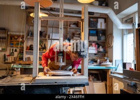 Uomo professionista falegname che lavora con attrezzature per falegnameria. Installazione di pannelli di legno sulla macchina Foto Stock