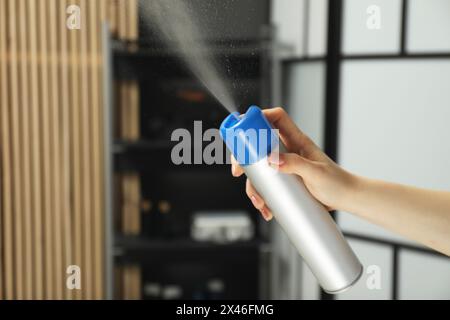 Donna spruzzante deodorante per ambienti a casa, primo piano. Spazio per il testo Foto Stock