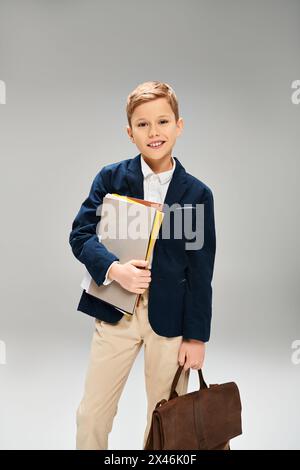 Ragazzo vestito con un abbigliamento elegante in possesso di un libro e di una valigetta. Foto Stock