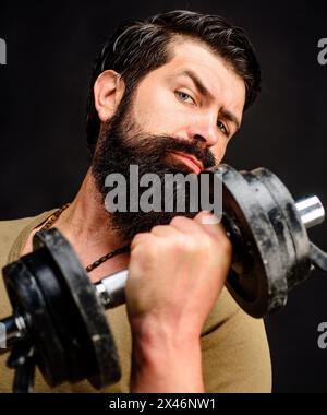 Forte barba e muscoloso sportivo che solleva il manubrio. Ritratto di primo piano. Culturisti sportivi che pompano i muscoli con il manubrio. Sollevamento pesi e bodybuilding Foto Stock