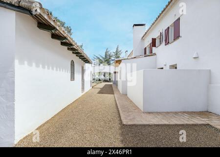 Facciate bianche di una casa di campagna andalusa in stile cortijo con finestre con persiane rosse in legno e pavimenti in terracotta Foto Stock