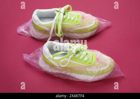 Sneakers con copriscarpe su sfondo rosa, primo piano Foto Stock