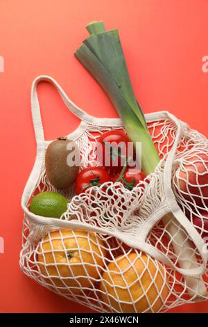 Sacchetto con spago con verdure e frutta diverse su sfondo rosso, vista dall'alto Foto Stock