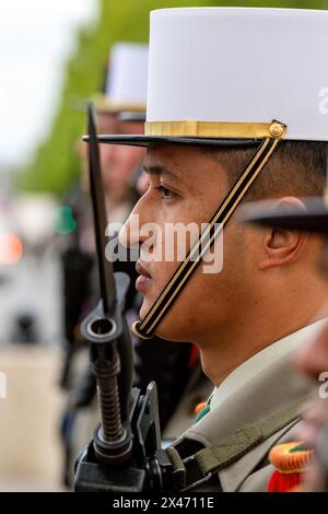 Un legionario si trova all'attenzione durante una cerimonia di rinascita amichevole per gli ex allievi delle unità della Legione straniera di Parigi e della Legione straniera all'Arco di Trionfo di Parigi. Sullo sfondo dell'Arco di Trionfo, Parigi, ex allievi e unità della Legione straniera di Parigi tennero un incontro cerimoniale. Aderendo alla tradizione, l'evento onora l'eredità di servizio e sacrificio della Legione. I veterani e i membri attivi partecipano alle formalità, comprese le presentazioni delle bandiere e le cerimonie delle medaglie. L'evento sottolinea il significato storico dell'unità all'interno dell'esercito francese e commemora il suo duraturo co Foto Stock