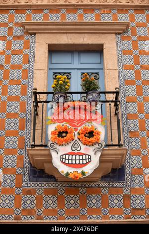 Bernal, Querétaro, Messico - 20 novembre 2023: Le decorazioni del Día de los Muertos sono appese all'esterno della finestra di un edificio piastrellato. Foto Stock