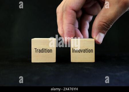 Scegliere l'innovazione al posto del concetto di tradizione. Blocchi di legno su sfondo nero. Foto Stock