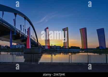 01 maggio 2024, Brandeburgo, Francoforte (Oder): Le bandiere ondeggiano al vento all'alba di fronte al ponte cittadino sul fiume Oder tra Francoforte (Oder) e Slubice in Polonia. In occasione del ventesimo anniversario dell'adesione della Polonia all'Unione europea, i ministri degli Esteri dei due paesi vicini vogliono riunirsi a mezzogiorno. Entrambi vogliono visitare il Collegium Polonicum a Slubice sul lato polacco, nonché un festival europeo, e poi camminare insieme attraverso il ponte della città sul confine tedesco-polacco fiume Oder fino a Francoforte (Oder). Foto: Patrick Pleul/dpa Foto Stock