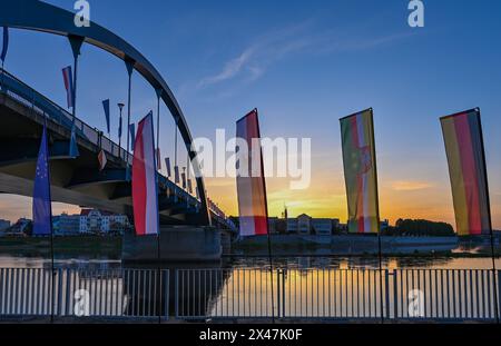 01 maggio 2024, Brandeburgo, Francoforte (Oder): Le bandiere ondeggiano al vento all'alba di fronte al ponte cittadino sul fiume Oder tra Francoforte (Oder) e Slubice in Polonia. In occasione del ventesimo anniversario dell'adesione della Polonia all'Unione europea, i ministri degli Esteri dei due paesi vicini vogliono riunirsi a mezzogiorno. Entrambi vogliono visitare il Collegium Polonicum a Slubice sul lato polacco, nonché un festival europeo, e poi camminare insieme attraverso il ponte della città sul confine tedesco-polacco fiume Oder fino a Francoforte (Oder). Foto: Patrick Pleul/dpa Foto Stock