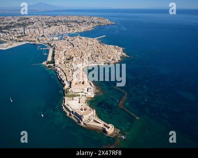 VISTA AEREA. L'isola di Ortigia e la città di Siracusa, l'Etna sono visibili in lontananza. Provincia di Siracusa, Sicilia, Italia. Foto Stock