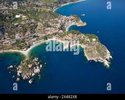 VISTA AEREA. I promontori rocciosi di Taormina che si estendono nel Mar Ionio. Città metropolitana di Messina, Sicilia, Italia. Foto Stock