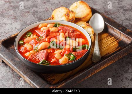 Stufato di crockpot con chorizo, fagioli di burro e spinaci da vicino in un recipiente servito con pane tostato sul tavolo. Orizzontale Foto Stock