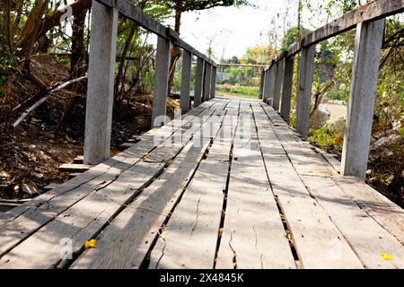 Ponte di legno che attraversa un fiume in un parco cittadino. Passerella di legno deserta che conduce via. Foto Stock