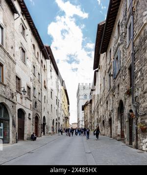 Gubbio, Italia - 27 aprile 2024: Via nel centro storico, con turisti. Sullo sfondo, Palazzo dei Consoli. Foto Stock