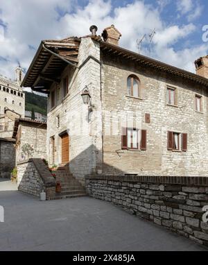 Gubbio, Italia - 27 aprile 2024: Casa nel centro storico. Sullo sfondo, il Palazzo dei Consoli. Foto Stock