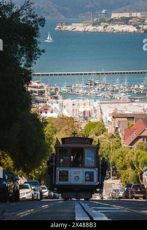 La funivia di San Francisco sale su Ripide Hill, con vista sull'isola di Alcatraz Foto Stock