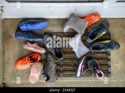 Assortimento di calzature per bambini poggiate sulla porta anteriore. Foto Stock