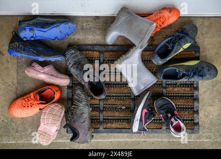 Assortimento di calzature per bambini poggiate sulla porta anteriore. Foto Stock