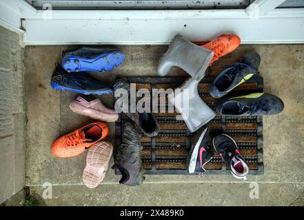 Assortimento di calzature per bambini poggiate sulla porta anteriore. Foto Stock