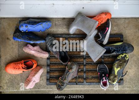 Assortimento di calzature per bambini poggiate sulla porta anteriore. Foto Stock