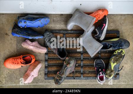 Assortimento di calzature per bambini poggiate sulla porta anteriore. Foto Stock