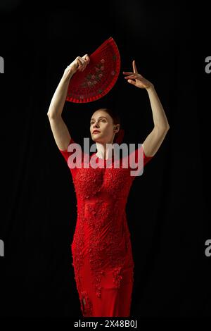 Ritratto creativo di una donna elegante in abito rosso, danza flamenco in posa su sfondo nero Foto Stock