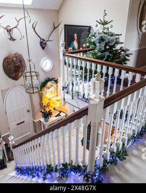 Scala a doppia altezza decorata con luci e agnello nella casa di famiglia Dorset a Natale, Inghilterra, Regno Unito Foto Stock