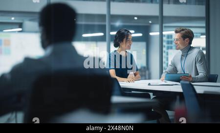 Diversi team di manager che lavorano e discutono nel moderno Big City Office. I colleghi lavorano su nuove opportunità di business, il CEO ha incontrato il dipendente e parla di investire nel futuro. Foto Stock