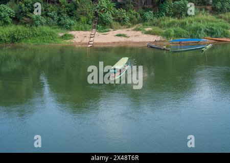 Una barca di legno sul fiume Nam Khan, che sfocia nel fiume Mekong, si trova a Luang Prabang, Laos, Asia. Foto Stock