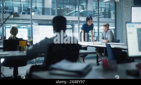 Diversi team di manager che lavorano e discutono nel moderno Big City Office. I colleghi lavorano su nuove opportunità di business, il CEO ha incontrato il dipendente e parla di investire nel futuro. Foto Stock