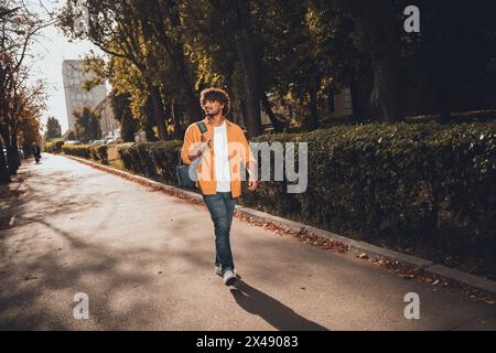 Foto di un simpatico e allegro uomo latino vestito con abiti alla moda che cammina alla scoperta della nuova città primavera stagione all'aperto Foto Stock