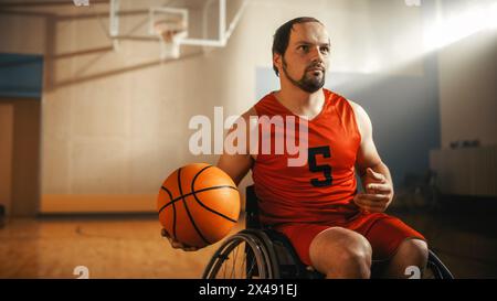 Ritratto di un bel giocatore di pallacanestro in sedia a rotelle che indossa la palla Dribbling Red Shirt, pronto a sparare alla perfezione. Persona determinata con disabilità che vincerà e sarà campione Foto Stock