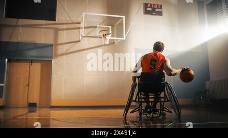 Giocatore di pallacanestro in sedia a rotelle che indossa una palla Dribbling rossa come un professionista. Determinazione, motivazione di una persona con disabilità che eccelle al Team Sport. Anonimo, immagine retrovisiva Foto Stock