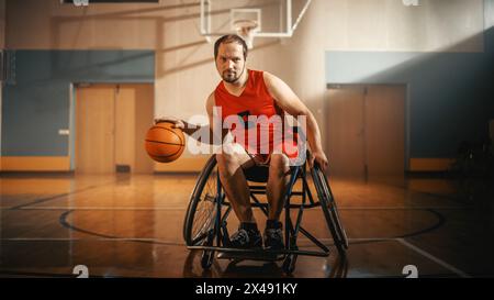 Ritratto di un bel giocatore di pallacanestro in sedia a rotelle che indossa la palla Dribbling della camicia rossa, guarda la fotocamera e sorride. Persona determinata con disabilità che vincerà e sarà campione Foto Stock