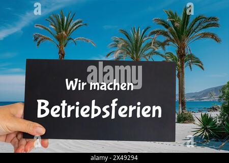 Immagine simbolo festività aziendali: Firma con l'iscrizione tedesca WIR MACHEN BETRIEBSFERIEN (siamo in vacanza aziendale) di fronte al mare, alla spiaggia e alle palme Foto Stock