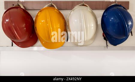 Caschi di sicurezza differenziati dal colore rosso, giallo, bianco e blu che sono appesi alla parete dell'ospedale Foto Stock