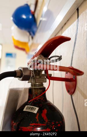 Primo piano del vecchio estintore con caschi di sicurezza colorati sullo sfondo Foto Stock