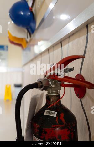 Primo piano del vecchio estintore con caschi di sicurezza colorati sullo sfondo Foto Stock