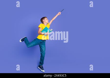 Foto di un ragazzo allegro in eleganti abiti gialli, salta in piedi il personaggio del genere narrativo del libro in attesa spazio vuoto isolato su sfondo di colore viola Foto Stock