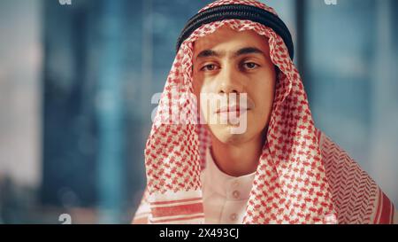 Ritratto di un uomo d'affari musulmano di successo in costume tradizionale che posa per la fotocamera, sorridendo dolcemente. Arabia Saudita, Emirati, concetto di uomo d'affari arabo. Foto Stock