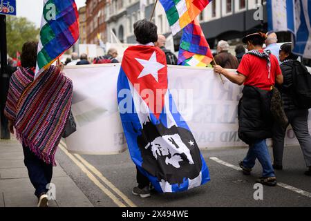 LONDRA, Regno Unito, 1° maggio 2024: I lavoratori sindacali marciano da Clerkenwell Green a Trafalgar Square nell'annuale rally del giorno di maggio di Londra. Il raduno è una celebrazione della solidarietà tra i lavoratori di tutto il mondo e una dimostrazione per la piena occupazione, i servizi pubblici, l'uguaglianza, l'antirazzismo e i diritti all'occupazione. Una donna è drappeggiata nella bandiera cubana raffigurante l'immagine di che Guevara. Foto Stock