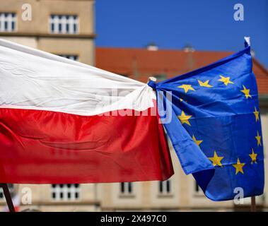 Bandiera nazionale della Polonia legata con la bandiera dell'UE nel centro della città contro edifici e cielo blu Foto Stock