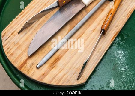 Una tavola di legno con un coltello, un paio di forbici e un paio di pinze Foto Stock