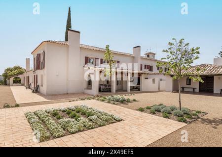 Una bella casa di campagna in stile andaluso con pareti bianche, sentieri di ghiaia e una varietà di piante recentemente piantate nel giardino Foto Stock